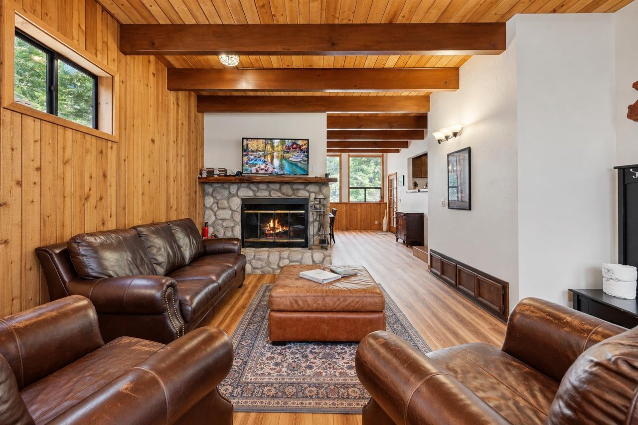 Sink into the leather sofas and take in mountain views through the wall of windows — this cozy living room is the heart of the cabin, with a flatscreen TV and warm woodbeamed ceilings overhead.