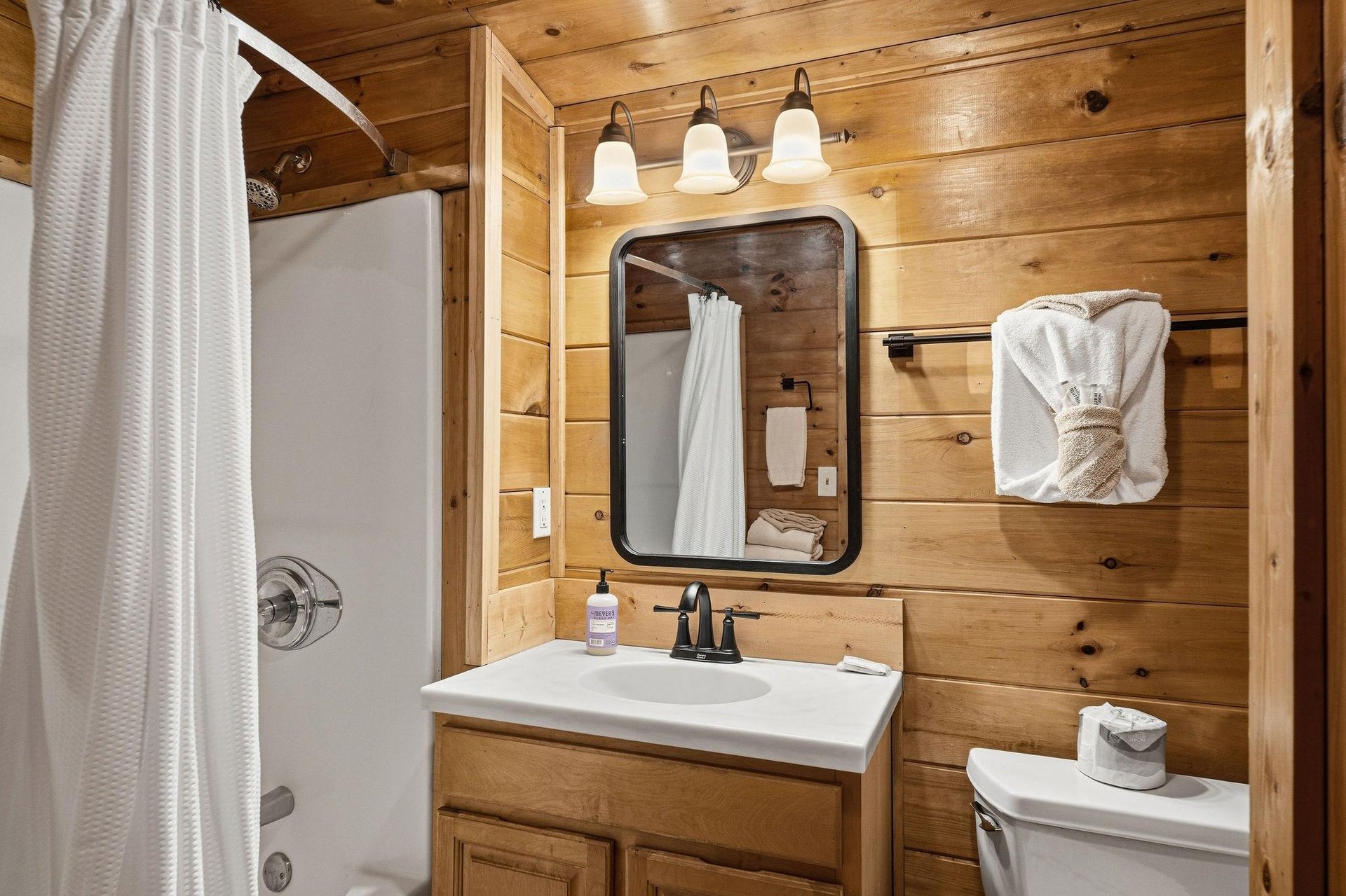 Unwind in your rustic bathroom featuring warm wood walls, modern fixtures, and fluffy towels waiting for your relaxing soak.