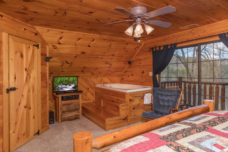 Bedroom with private deck access, in room jacuzzi, and TV at Hidden Pleasure, a 1bedroom cabin rental located in Gatlinburg