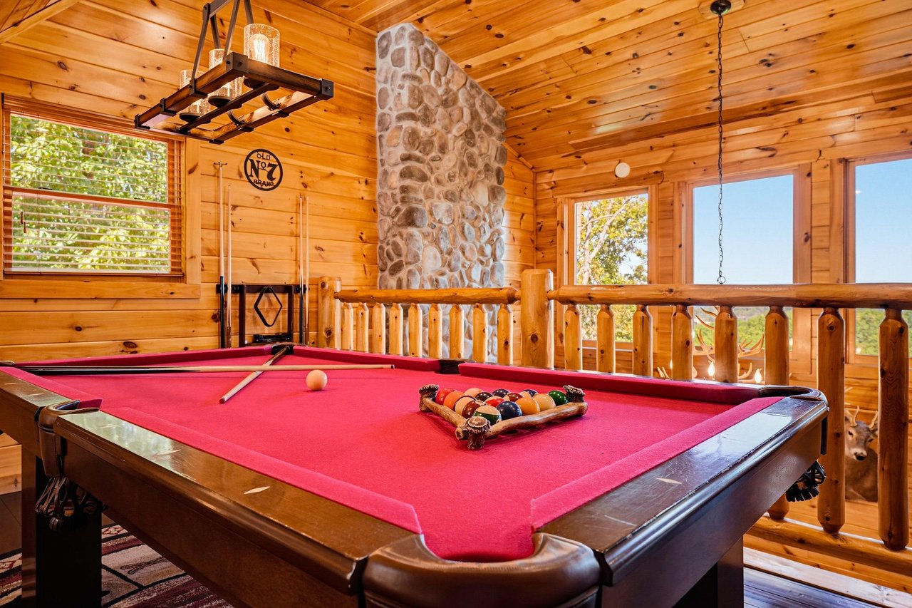 Challenge friends to a game in this cozy loft space, where warm wood beams and a stunning stone fireplace create the perfect setting for memorable evenings.