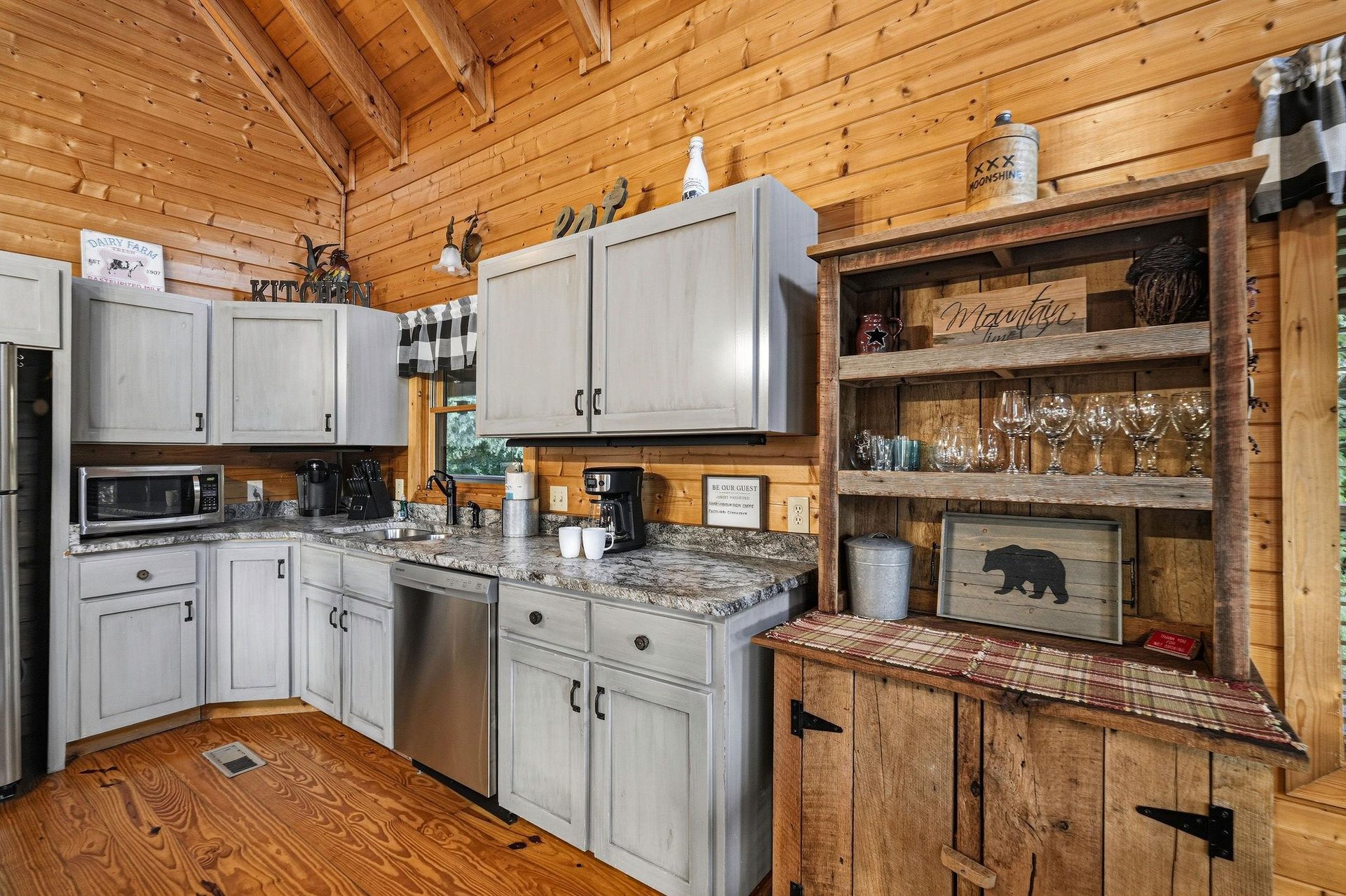 Step into your inviting mountain cabin kitchen, where rustic wood charm meets modern convenience. The vaulted pine ceiling and cozy décor create a warm retreat for cooking and gathering.