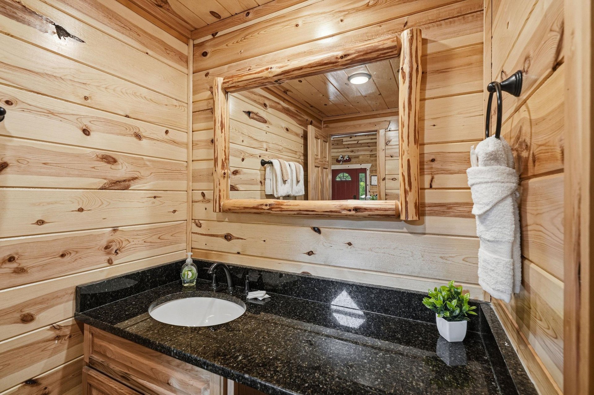 Freshen up in your rustic cabin bathroom with warm wood accents and a sleek granite vanity, complete with all the essentials for your mountain retreat.