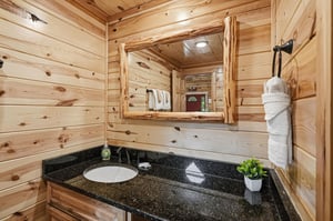 Freshen up in your rustic cabin bathroom with warm wood accents and a sleek granite vanity, complete with all the essentials for your mountain retreat.