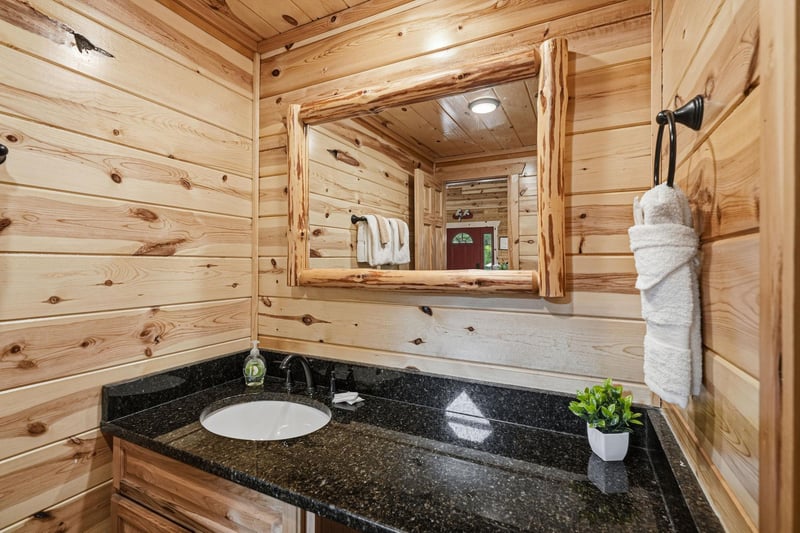 Freshen up in your rustic cabin bathroom with warm wood accents and a sleek granite vanity, complete with all the essentials for your mountain retreat.