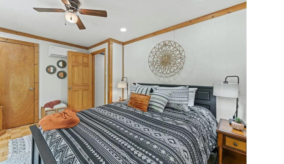 Your cozy bedroom features warm wood accents, a ceiling fan for comfort, and stylish geometric bedding that creates the perfect retreat.