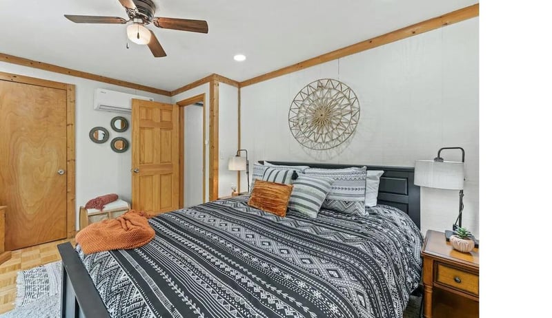 Your cozy bedroom features warm wood accents, a ceiling fan for comfort, and stylish geometric bedding that creates the perfect retreat.