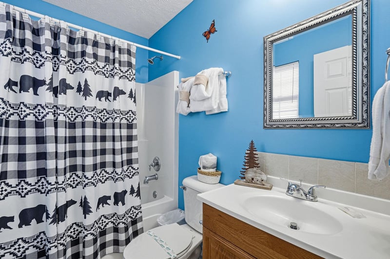 Unwind in your charming cabinthemed bathroom with cheerful blue walls, fresh towels, and woodsy bear decor that makes you feel cozy.