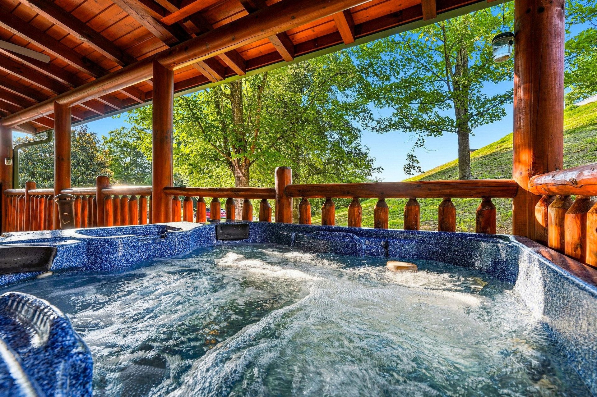 Slip into your private hot tub and let the warm, bubbling water soothe you as you gaze out at lush trees and rolling hills under a bright blue sky.