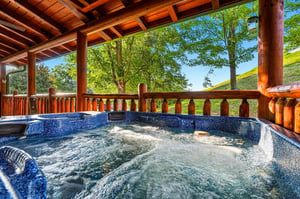 Slip into your private hot tub and let the warm, bubbling water soothe you as you gaze out at lush trees and rolling hills under a bright blue sky.