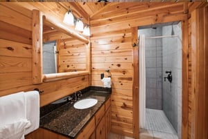 Unwind in your rustic bathroom featuring warm wood walls, granite counters, and a spacious walkin shower perfect for refreshing after mountain adventures.