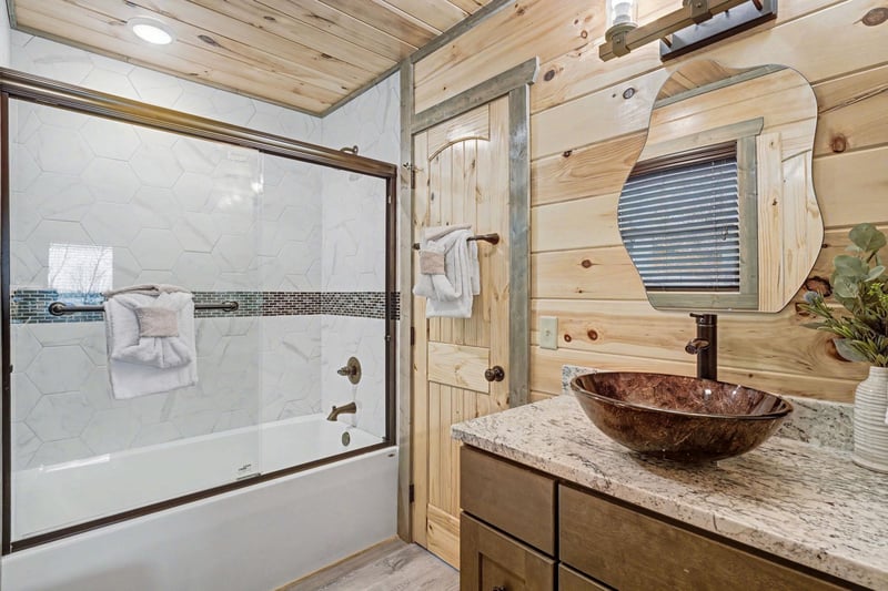 Your rustic bathroom combines cabin charm with modern amenities, featuring a luxurious vessel sink and relaxing tubshower.