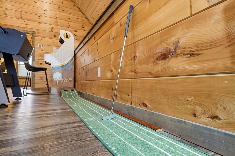Practice your putting skills in this cozy indoor mini golf setup, complete with rustic wood walls and comfortable seating area.