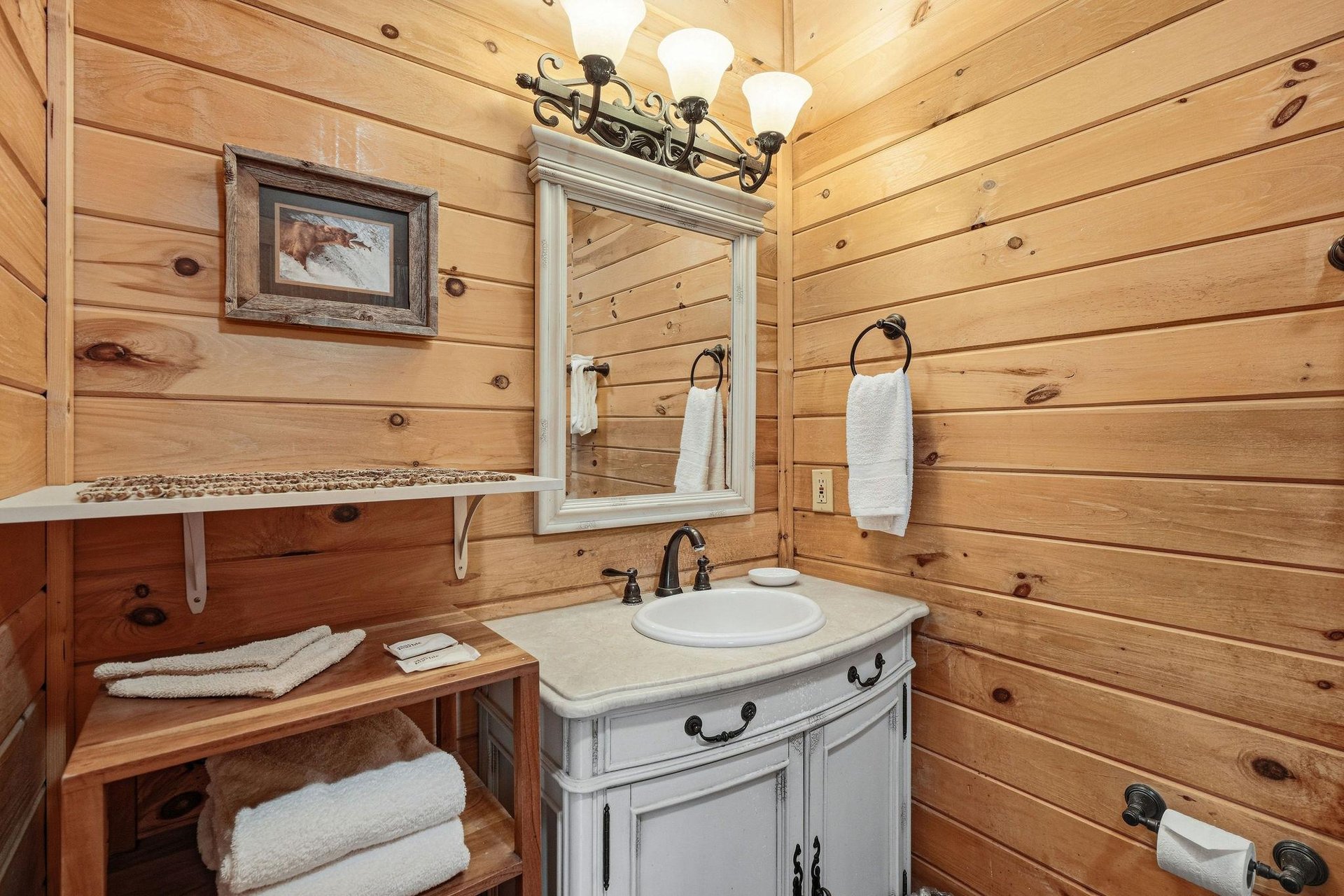 Step into your rustic bathroom where warm wood walls create a cozy cabin feel, complete with elegant vanity and fluffy towels.