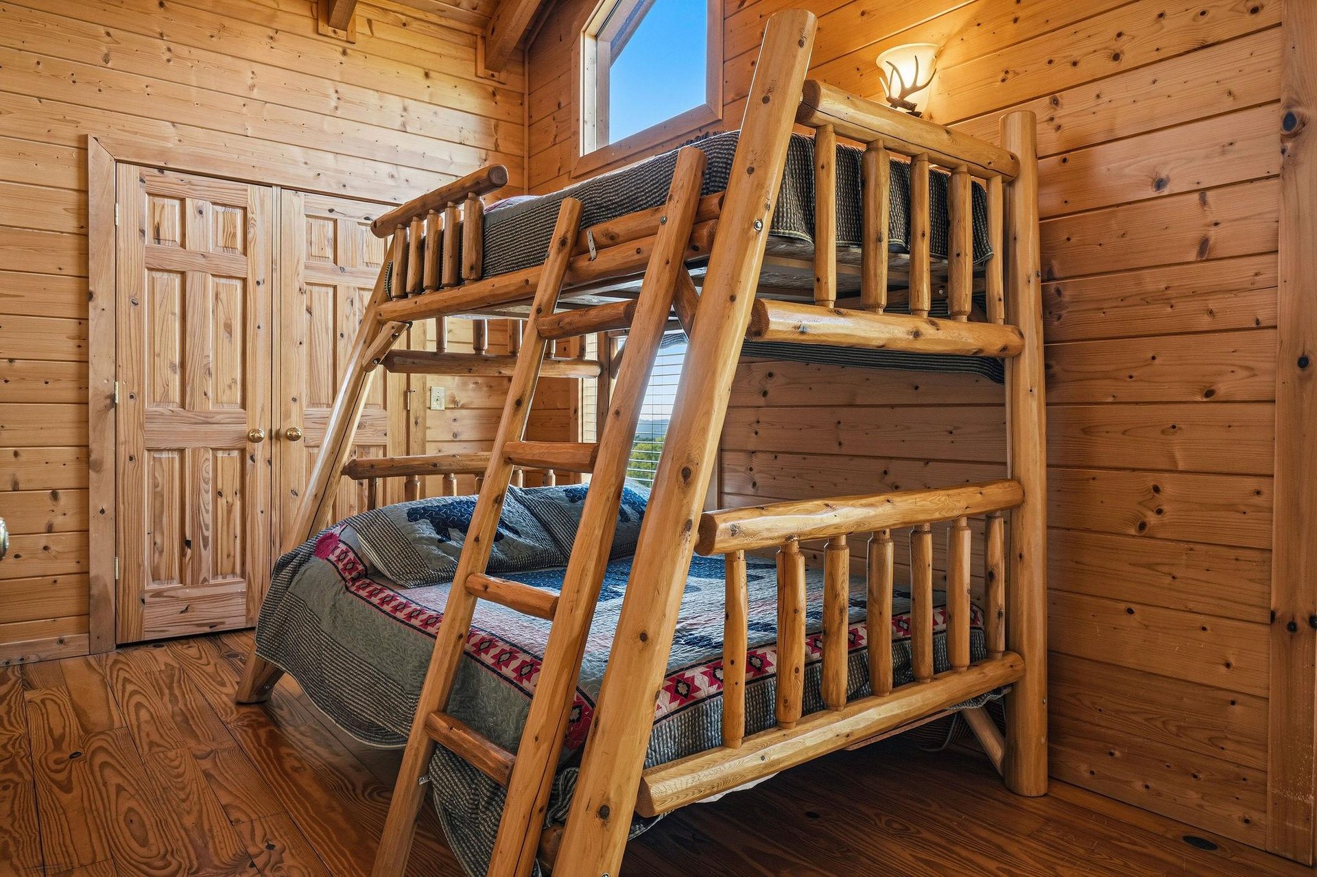Cozy up in this charming log cabin bedroom featuring a sturdy bunk bed—perfect for kids or groups. Natural wood walls and warm lighting create a welcoming mountain retreat feel.