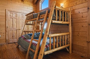 Cozy up in this charming log cabin bedroom featuring a sturdy bunk bed—perfect for kids or groups. Natural wood walls and warm lighting create a welcoming mountain retreat feel.