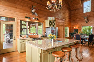 Your rustic mountain retreat features a stunning kitchen where youll love gathering around the granite island with handcrafted log stools, surrounded by warm wood walls and natural light streaming th