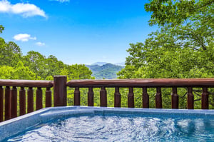 Soak away your cares with sweeping mountain views stretching into the distance, framed by lush green trees and endless blue skies.
