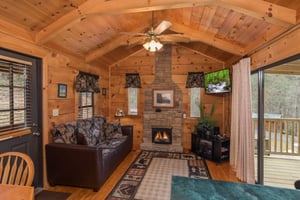 Stone fireplace, TV, and sofa in the living room at Boogie Bear, a 1bedroom cabin rental located in Gatlinburg