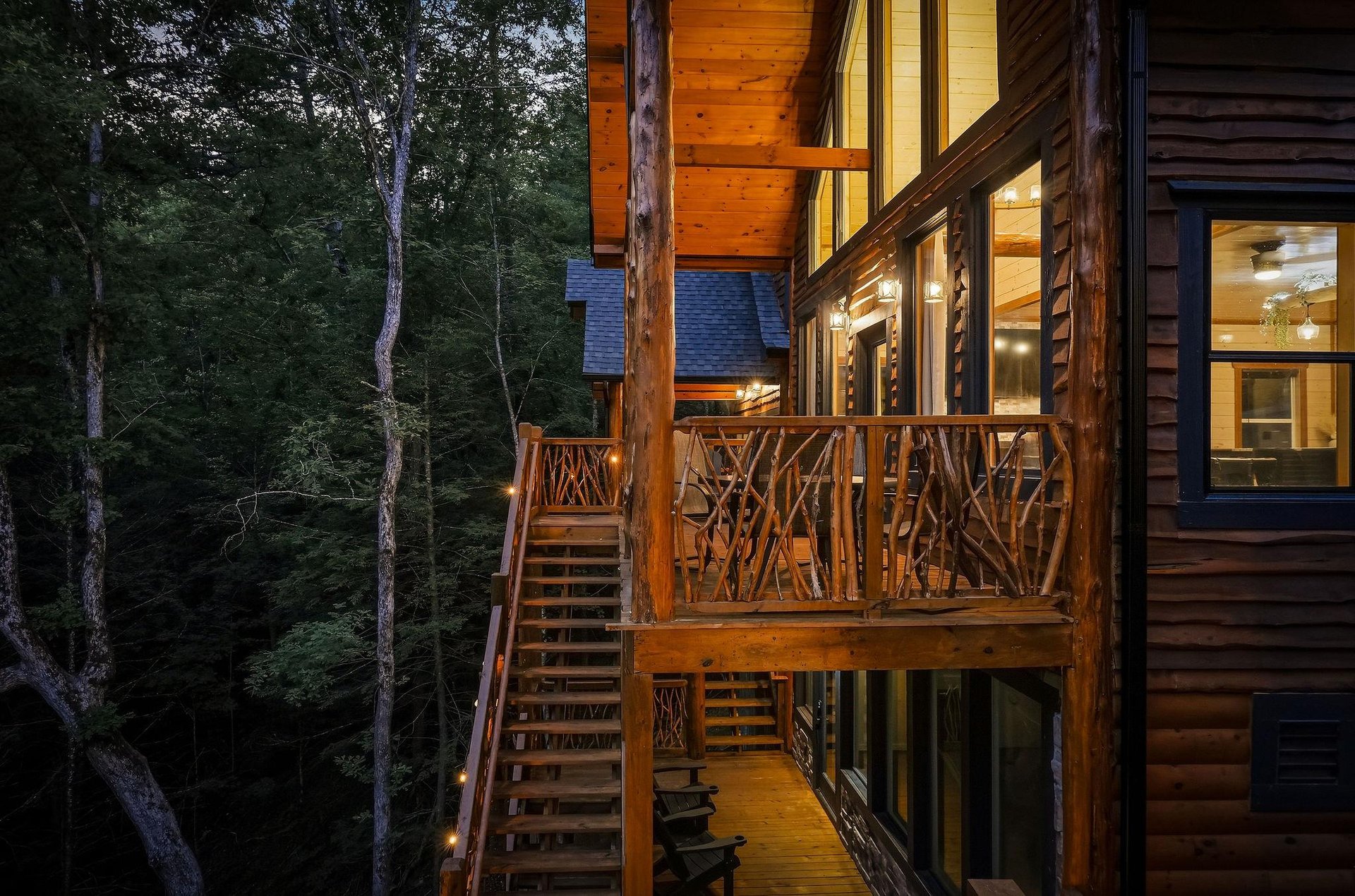 Rustic wood cabin exterior with handcrafted twig railings and warmlit interiors illuminates the serene forest setting at twilight.