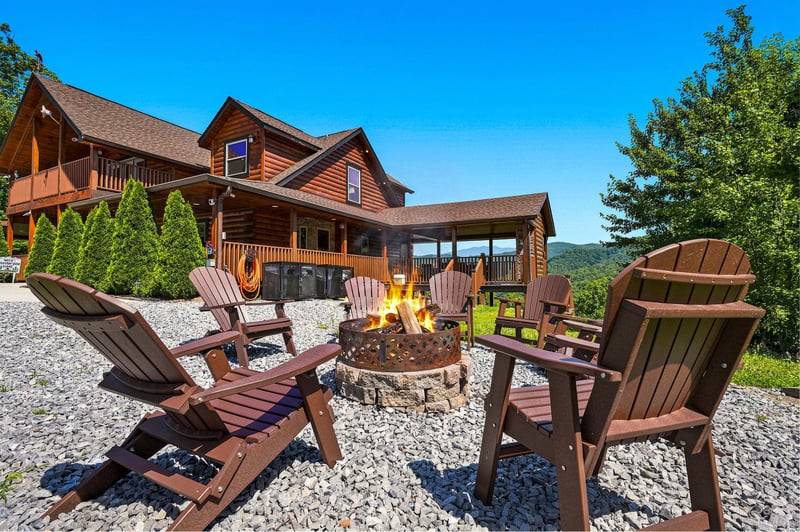 Rustic mountain lodge with spacious deck overlooking wooded hills. Outdoor fire pit circle invites cozy mountain evenings under open skies.