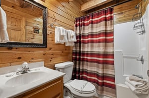 Cozy cabin bathroom with warm knotty pine walls, fresh towels waiting for you, and a shower to refresh after your adventures. The rustic wood beams and thoughtful touches make this space feel like hom