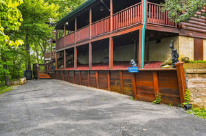 A charming log cabin nestled among lush trees, featuring spacious balconies and a private driveway, offering a peaceful mountain retreat.
