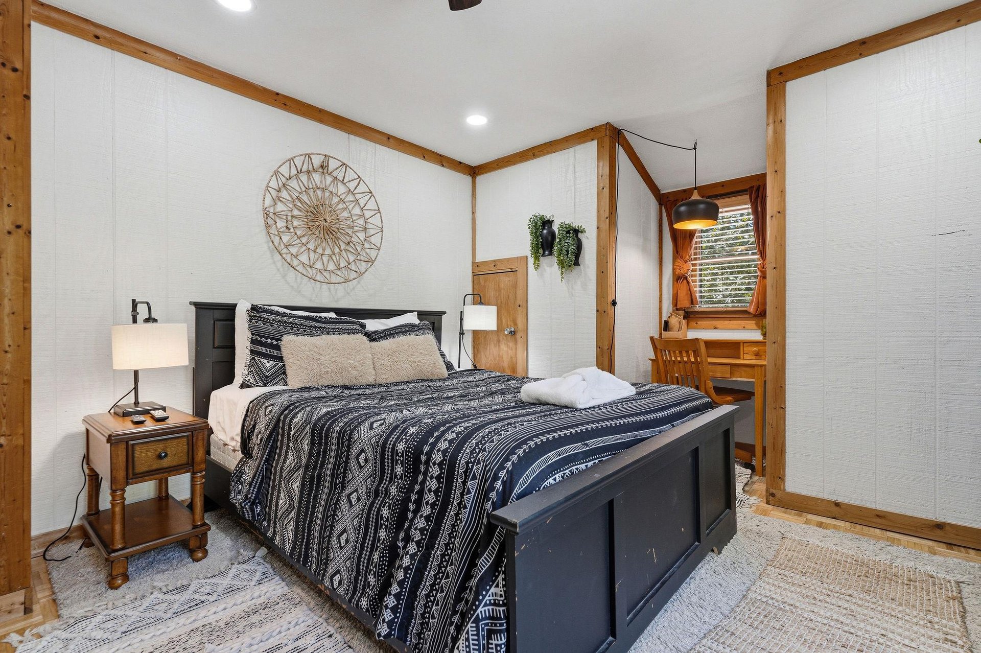 Sink into this cozy bedroom where rustic wood beams meet modern comfort, complete with stylish bedding and warm lighting for your perfect retreat.