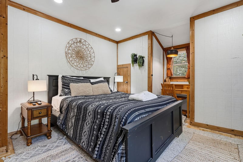 Sink into this cozy bedroom where rustic wood beams meet modern comfort, complete with stylish bedding and warm lighting for your perfect retreat.