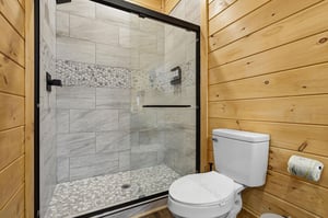 Step into your private spa retreat with this stunning stonetiled shower featuring elegant mosaic accents and sleek glass doors.