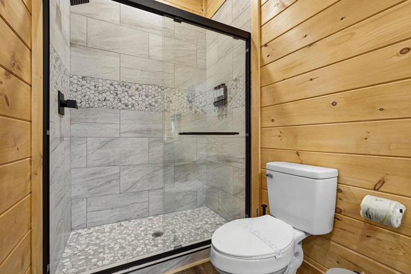 Step into your private spa retreat with this stunning stonetiled shower featuring elegant mosaic accents and sleek glass doors.
