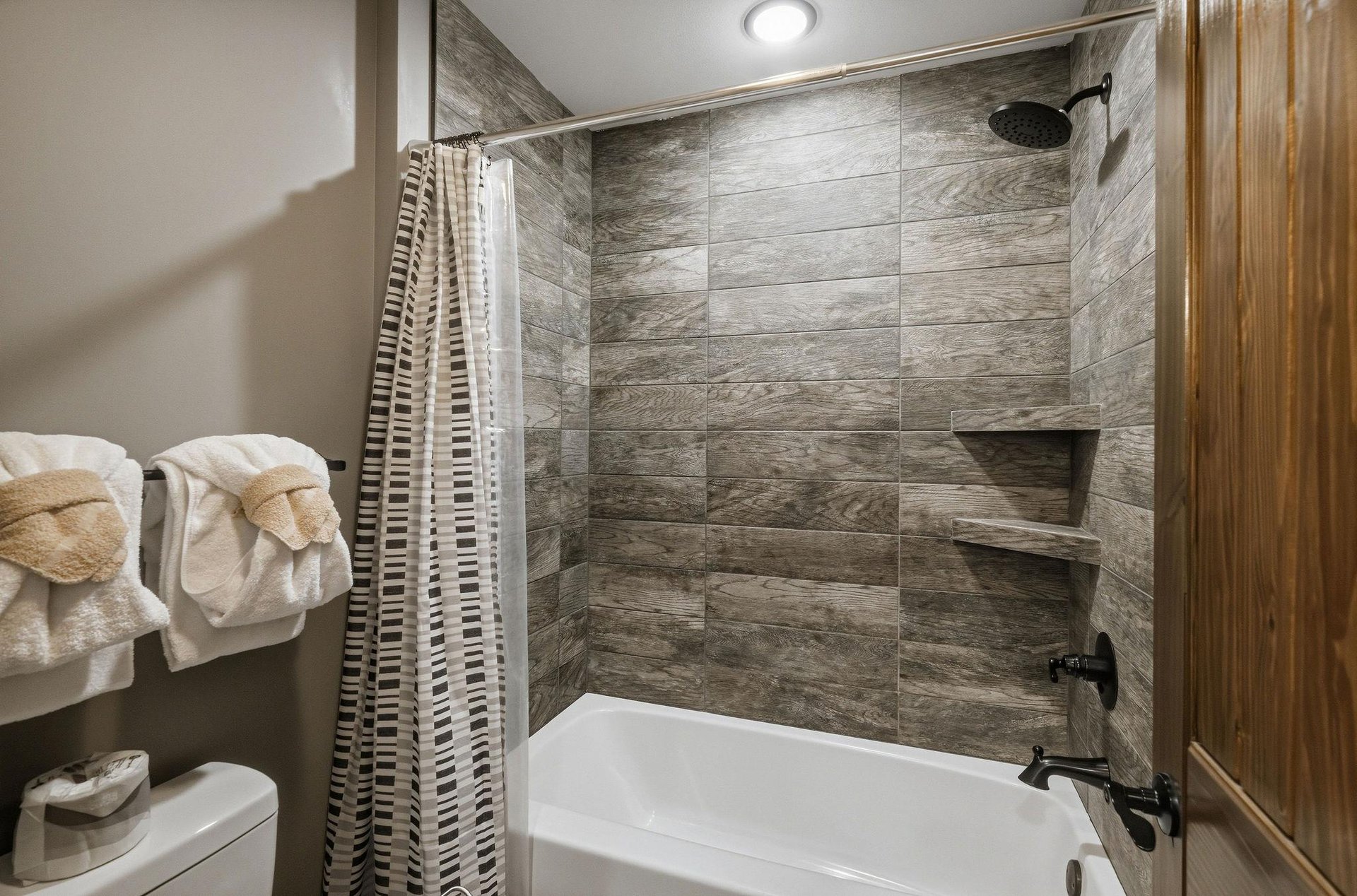 Your private bathroom features modern woodlook tile, a rainfall shower, and a deep soaking tub—with fresh towels and everything you need to unwind after your day.