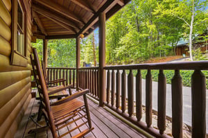 Step onto your private covered porch and settle into the rocking chairs, surrounded by lush summer greenery—a perfect spot to unwind and soak in the mountain air.