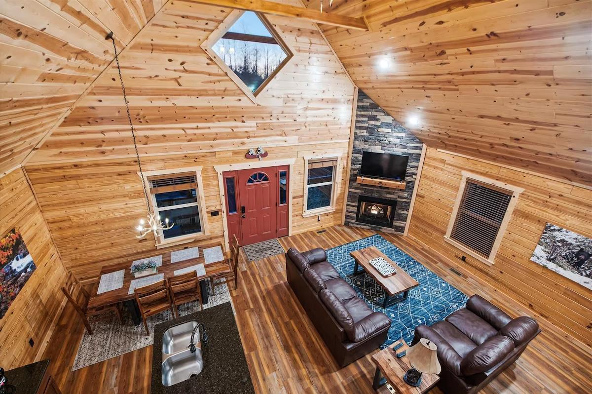 Unwind in this stunning cabins vaulted living space, where leather recliners face a cozy fireplace under soaring woodbeam ceilings.