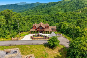Aerial view of a charming mountain lodge nestled among forested peaks, offering serene natural surroundings and privacy in a picturesque landscape.