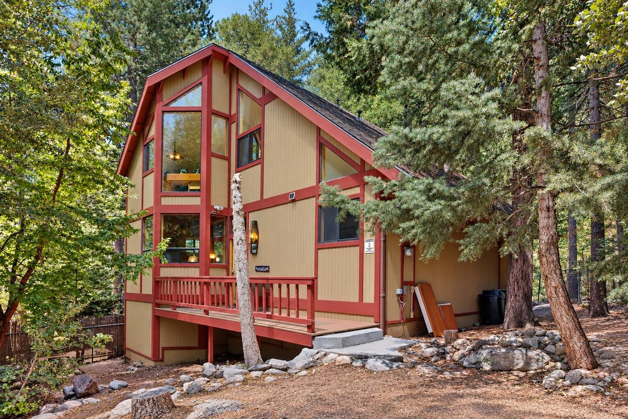Another look at Strawberry Creek Cabins striking Aframe design, with tall windows and red trim rising up among the trees — a true mountain retreat from every angle.
