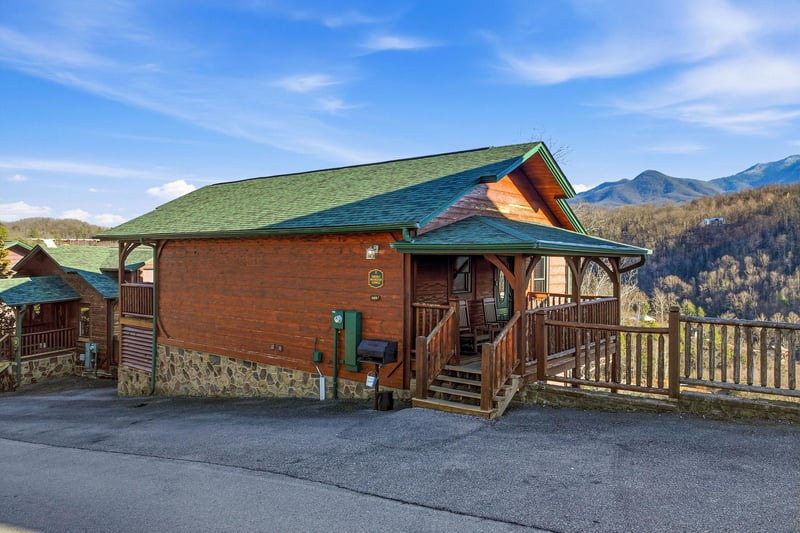 Mountainview cabin with wooden deck and striking multicolored roof nestled in scenic foothills.