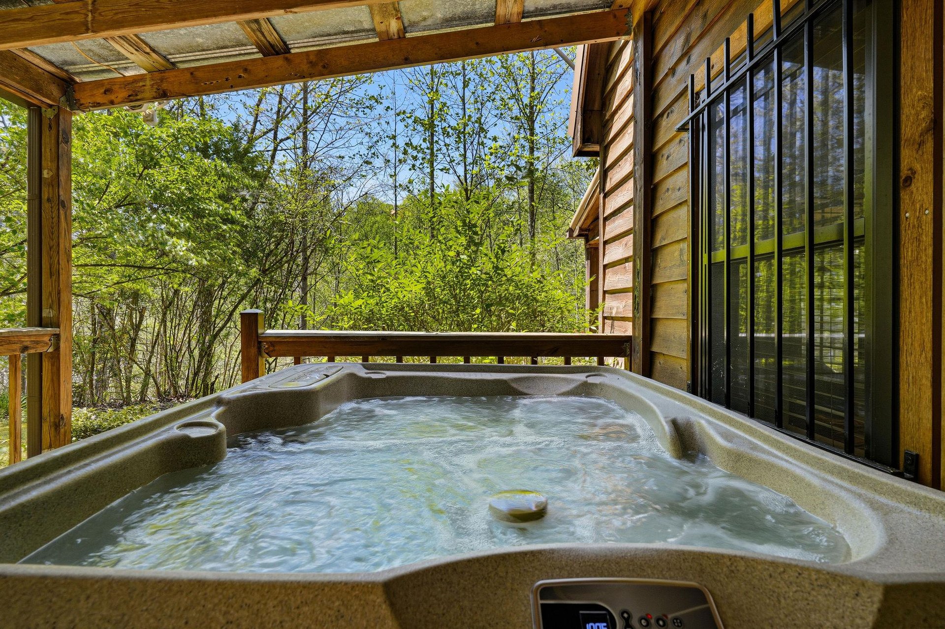 Soak in your private hot tub while surrounded by lush forest views from your covered deck retreat.