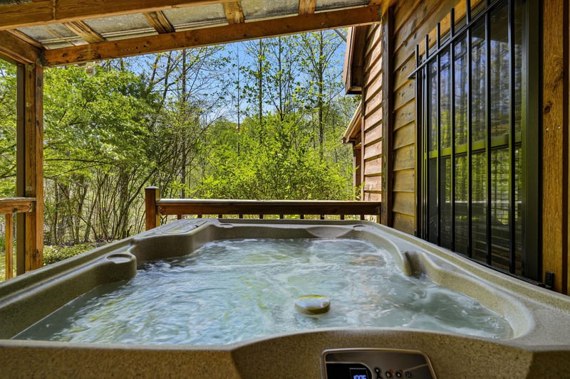 Soak in your private hot tub while surrounded by lush forest views from your covered deck retreat.