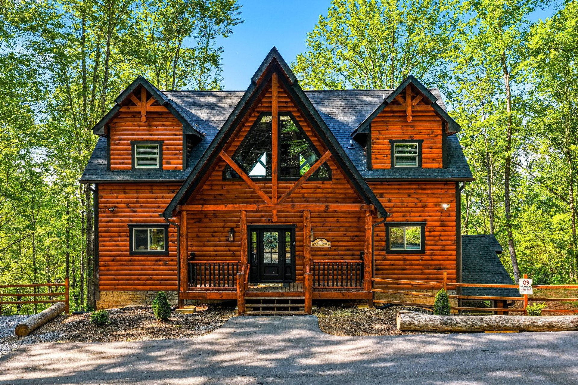 Beautiful log cabin retreat nestled among towering trees, featuring classic mountain architecture with a welcoming covered porch.