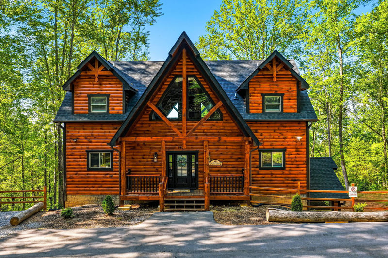 Beautiful log cabin retreat nestled among towering trees, featuring classic mountain architecture with a welcoming covered porch.