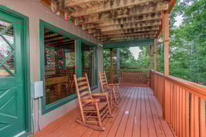Deck with rocking chairs and a porch swing at Bushwood Lodge, a 3bedroom cabin rental located in Gatlinburg