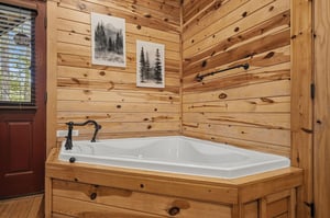 Soak away your stress in this luxurious corner tub, surrounded by warm wood walls and mountain artwork for the perfect cabin retreat.