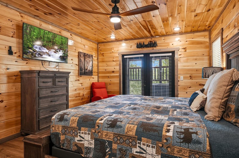 Drift off to sleep in your cozy cabin bedroom, surrounded by warm wood walls and rustic charm that makes every night feel like a mountain retreat.