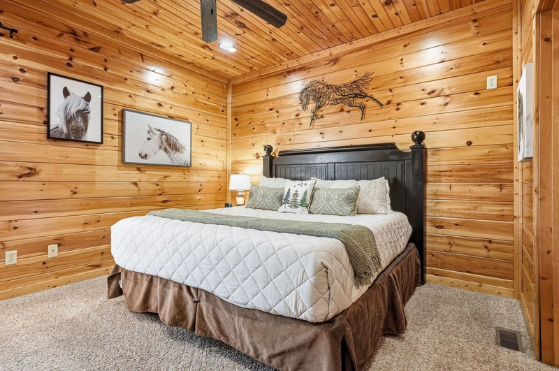Drift off in your cozy rustic bedroom, surrounded by warm wood walls and charming horse artwork that creates the perfect mountain retreat atmosphere.