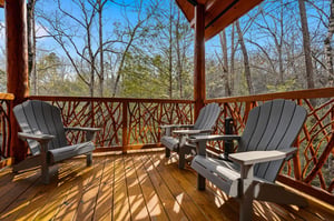 Unwind on your private covered deck with comfortable Adirondack chairs, surrounded by peaceful forest views that create the perfect retreat.