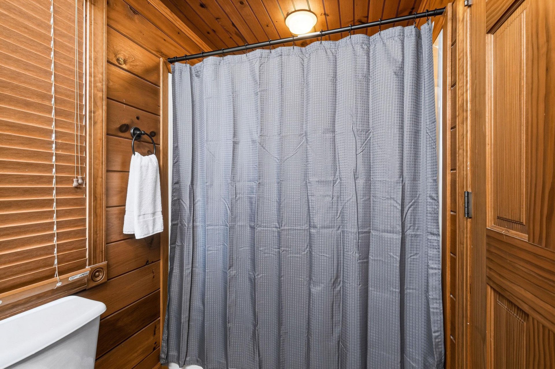Step into the warmth of natural wood paneling and enjoy a refreshing shower in this cozy, cabinstyle bathroom with crisp linens and rustic charm.