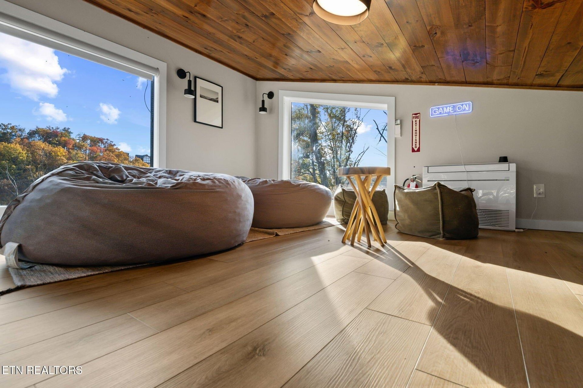 Sink into oversized bean bags beneath warm wood ceilings as natural light pours through large windows framing autumn foliage outside.