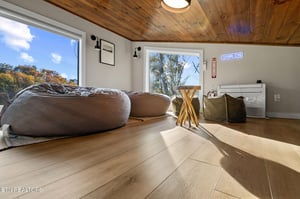 Sink into oversized bean bags beneath warm wood ceilings as natural light pours through large windows framing autumn foliage outside.