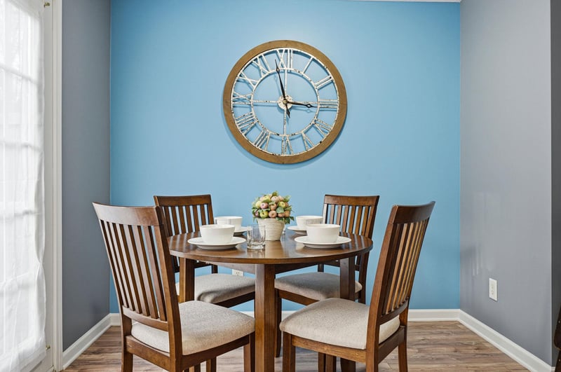Your dining table awaits, perfectly set for intimate meals beneath a charming accent wall that adds warmth to every gathering.