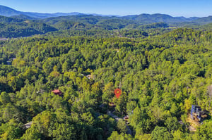 This aerial view captures the property nestled within lush forested mountains, offering a peaceful escape surrounded by natural beauty and stunning scenic vistas.